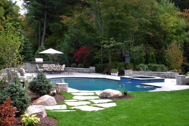 The Natural Landscape Inc. – Sterling stone walls, fire pit and outdoor kitchen; thermal bluestone pool coping, pool deck and wall caps; Uba Tuba granite countertop